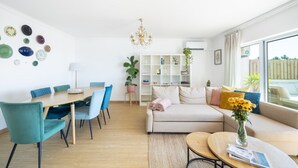 Un salon moderne comprenant un coin repas, un ensemble de canapés, un lustre et une bibliothèque.