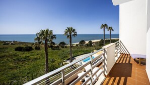 Un balcon avec piscine, donnant sur une plage et l’océan.