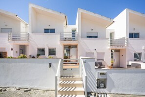 A modern multi-story residential building with balconies, a central staircase, and a small outdoor seating area. - Nativo Big Wave 2BR - Best location to see big waves - Swimming pool (Nazaré)