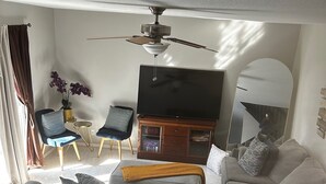 A living room with a sofa, chairs, a TV, a ceiling fan, and a large mirror. - Exquisite gated private townhouse in the beautiful Palm Bay (Palm Bay)