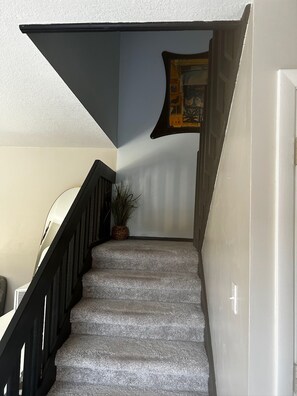 Eine Treppe mit schwarzer Geländer, einem Blumentopf und einem Bild an der Wand.