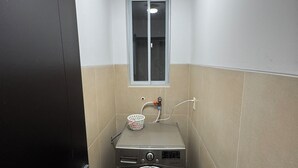 Une petite buanderie équipée d’un lave-linge, d’un étendoir et d’une fenêtre.
