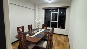 Un coin repas avec une table en bois, des chaises, un vase de fleurs et une vue sur le ciel nocturne par une fenêtre.
