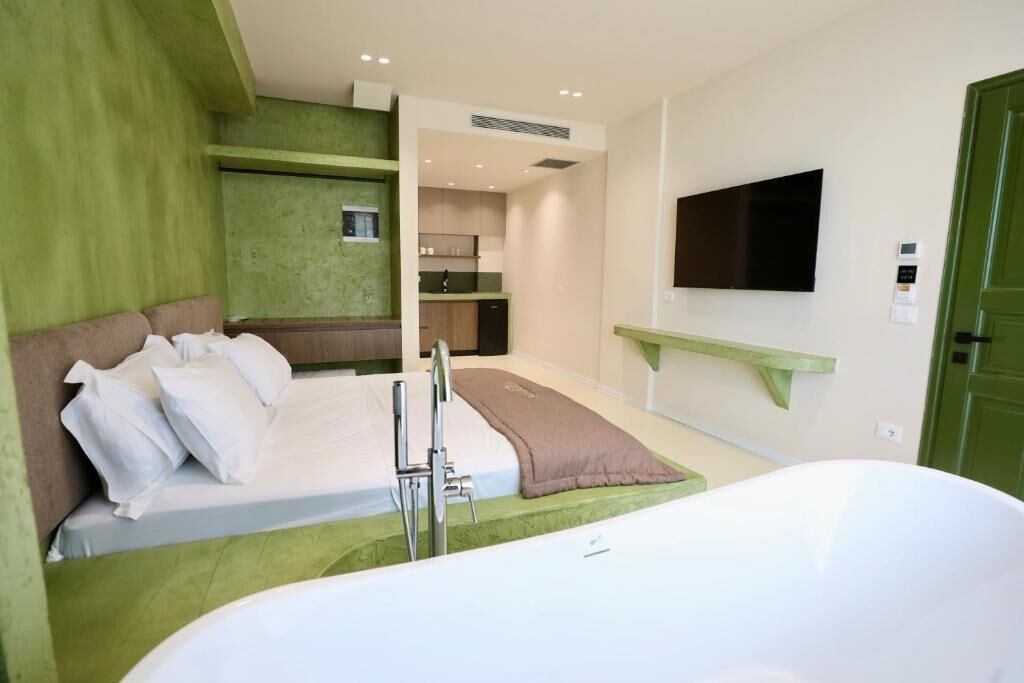 Una habitación de hotel moderna con cama, bañera, televisión y kitchenette.