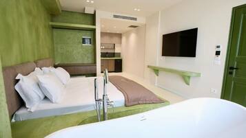 Una habitación de hotel moderna con cama, bañera, televisión y kitchenette.