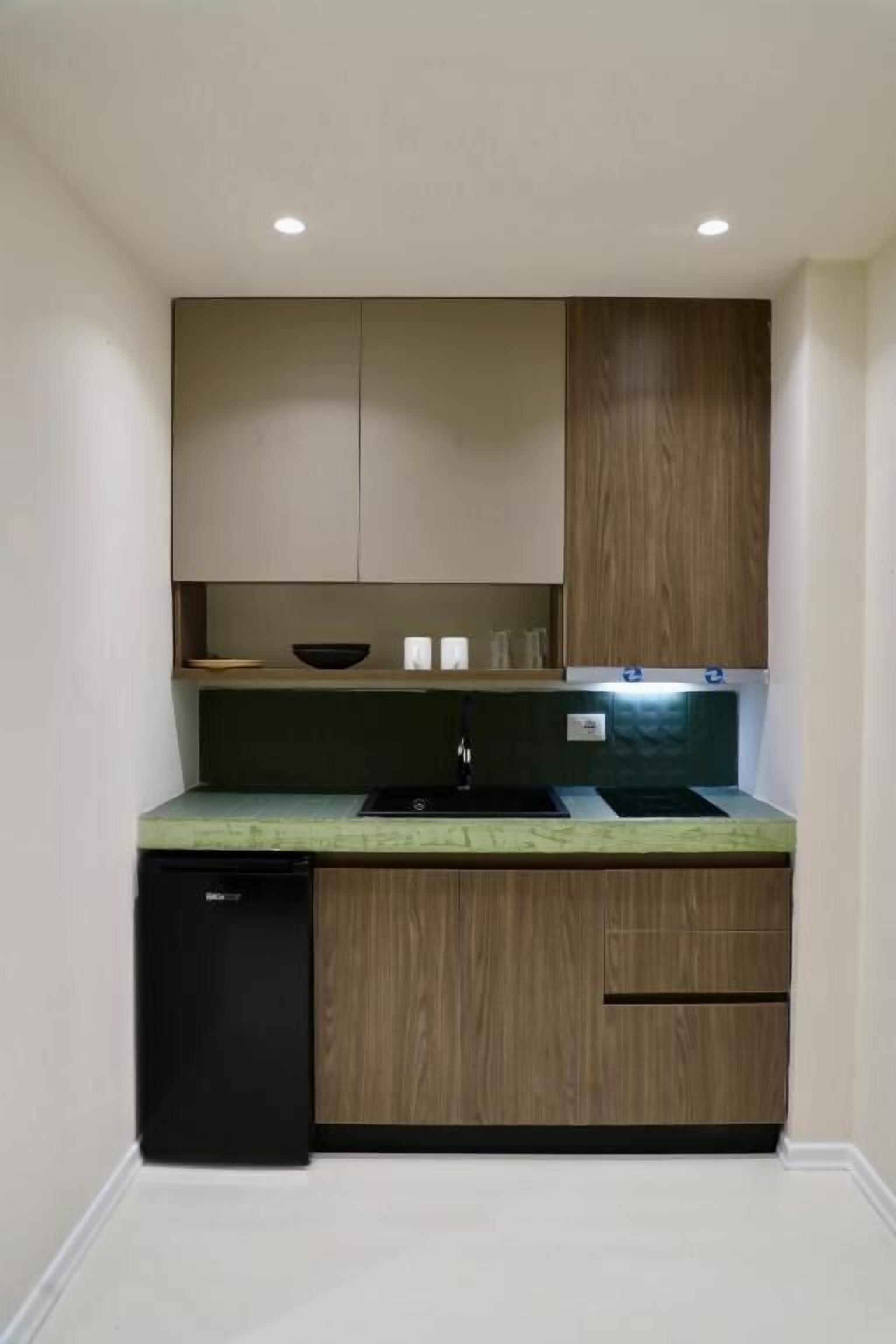 Une cuisine compacte dotée d’un lave-vaisselle intégré, de meubles en bois et d’un plan de travail vert.