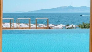 Une piscine d’un bleu éclatant, avec une vue sur la mer et les montagnes en arrière-plan.