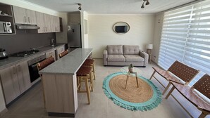 Una cocina moderna con una isla central, un comedor con mesa redonda y un sofá.
