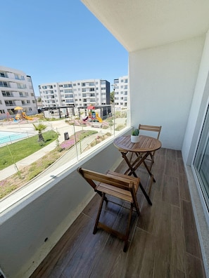 A balcony with a wooden table and chairs, a view of a playground, and residential buildings in the background. - Family apartment a few steps from the sea. (La Serena)