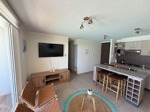 A modern kitchen with a flat-screen TV, wooden bar stools, and a central island. - Family apartment a few steps from the sea. (La Serena)