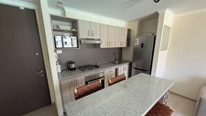 Una cocina moderna con una isla central, electrodomésticos integrados y una despensa.