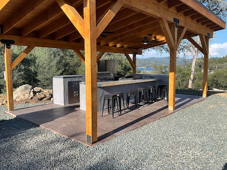A covered outdoor kitchen with a bar area, seating, and a built-in grill.. Moonshadow Flat Glamping Tents