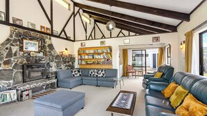 Ein gemütliches Wohnzimmer mit Kamin aus Stein, einem Ecksofa, einem Ledersofa und einem Bücherregal.