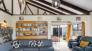 Ein Wohnzimmer mit einer Couch, einem Bücherregal, einem Ledersessel und einer Steinwand.
