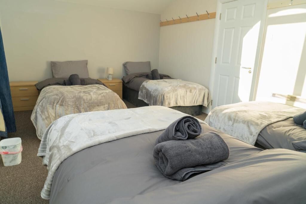Une chambre d’hôtel avec deux lits, une table de chevet, une commode et une porte.