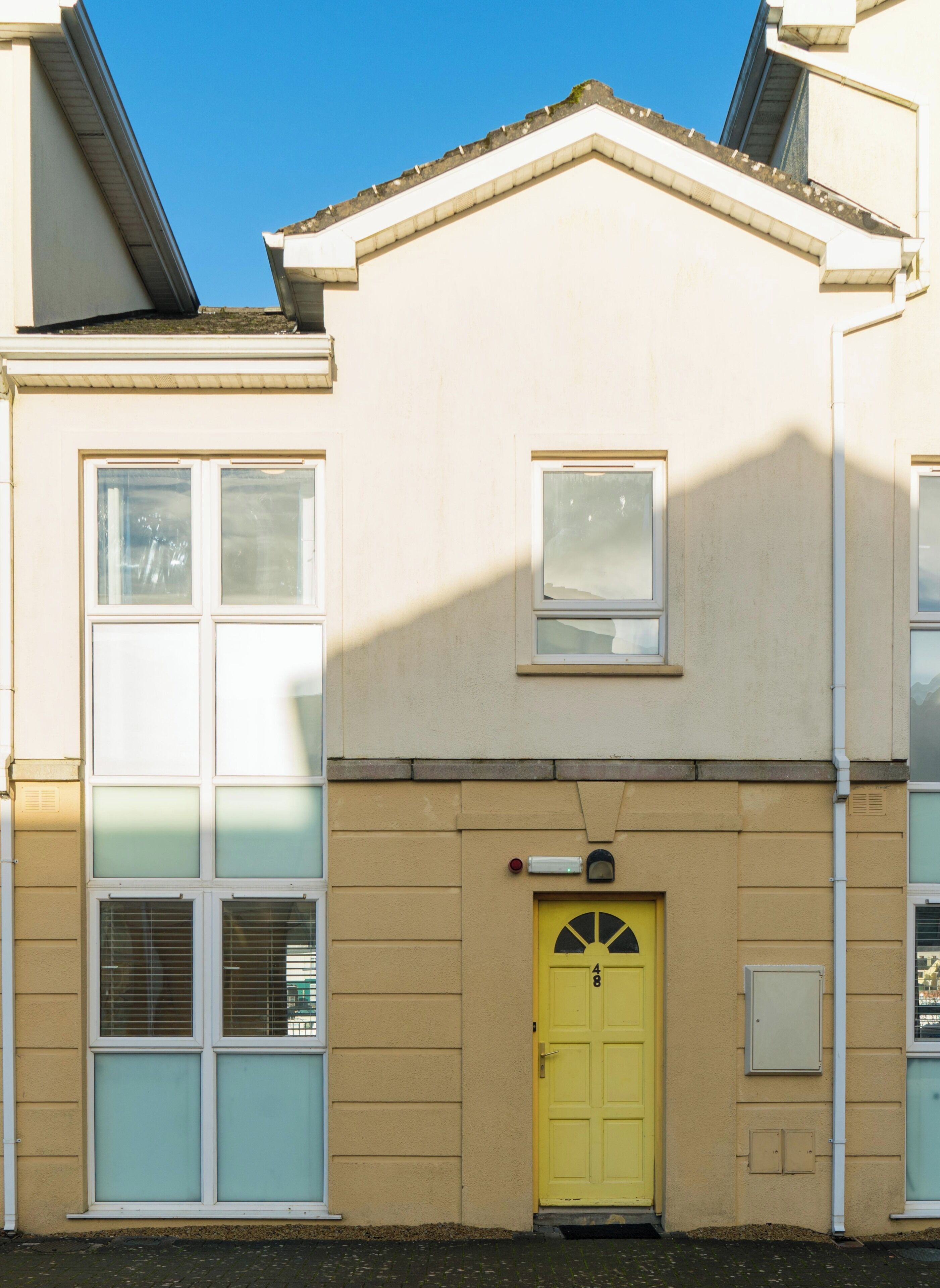 A building with a yellow door, multiple windows, and a small balcony.