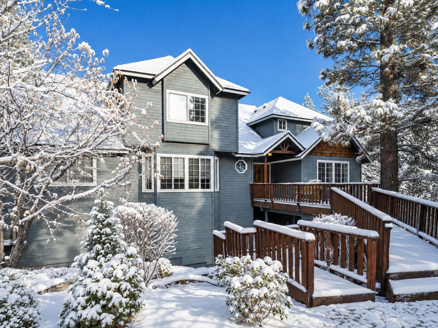 Una casa de dos pisos con un porche cubierto y un paisaje cubierto de nieve.