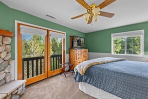 Une chambre à coucher avec un lit, un ventilateur de plafond, une commode et un téléviseur.