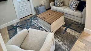 A loft-style living room with a high ceiling, a skylight, a sofa, a coffee table, and a chair. - Ocean light Deck + Patio • Central P-Town (Provincetown)