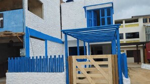 A building with a white exterior and blue accents, a wooden gate, and a blue roof structure. - Pousada Pé no Mar (Japaratinga)