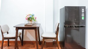 Una cocina con un refrigerador, dos sillas, una mesa y un florero con flores.