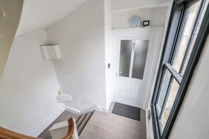 A staircase leading to a door with a frosted glass panel, a small shelf with a candle, and a doormat.