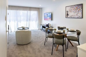 A modern dining area with a round table, six chairs, and a sofa. - Peaceful City Townhouse | 2 Bed+ Private Car Park (Christchurch)