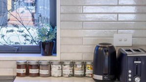 Una cocina con ventana, un tostador, un hervidor y frascos de condimentos.