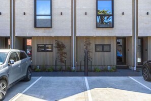A multi-story building with a parking lot, a car, and a small tree. - Peaceful City Townhouse | 2 Bed+ Private Car Park (Christchurch)
