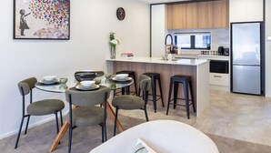 Una cocina moderna con una isla central, taburetes de bar y una mesa de comedor con sillas.