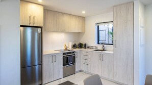 Una cocina moderna con electrodomésticos de acero inoxidable, armarios de madera clara y un ventanal que proporciona luz natural.
