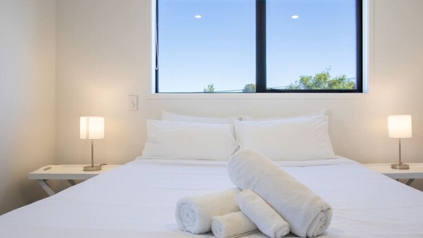 Habitación de hotel con una cama grande, dos lámparas de noche y una ventana con vistas a árboles.
