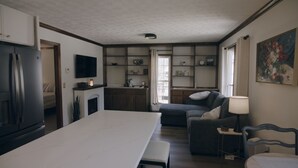 A modern kitchen with a dining area, a sofa, and a TV. - Luxurious 1-Bedroom Townhome in Peachtree City with AC (Peachtree City)
