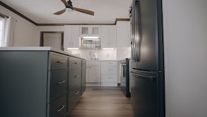 Une cuisine équipée d’un réfrigérateur, de placards et d’un ventilateur de plafond.