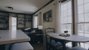 A cozy room with a dining table, a sofa, a chair, a lamp, and a painting. - Luxurious 1-Bedroom Townhome in Peachtree City with AC (Peachtree City)