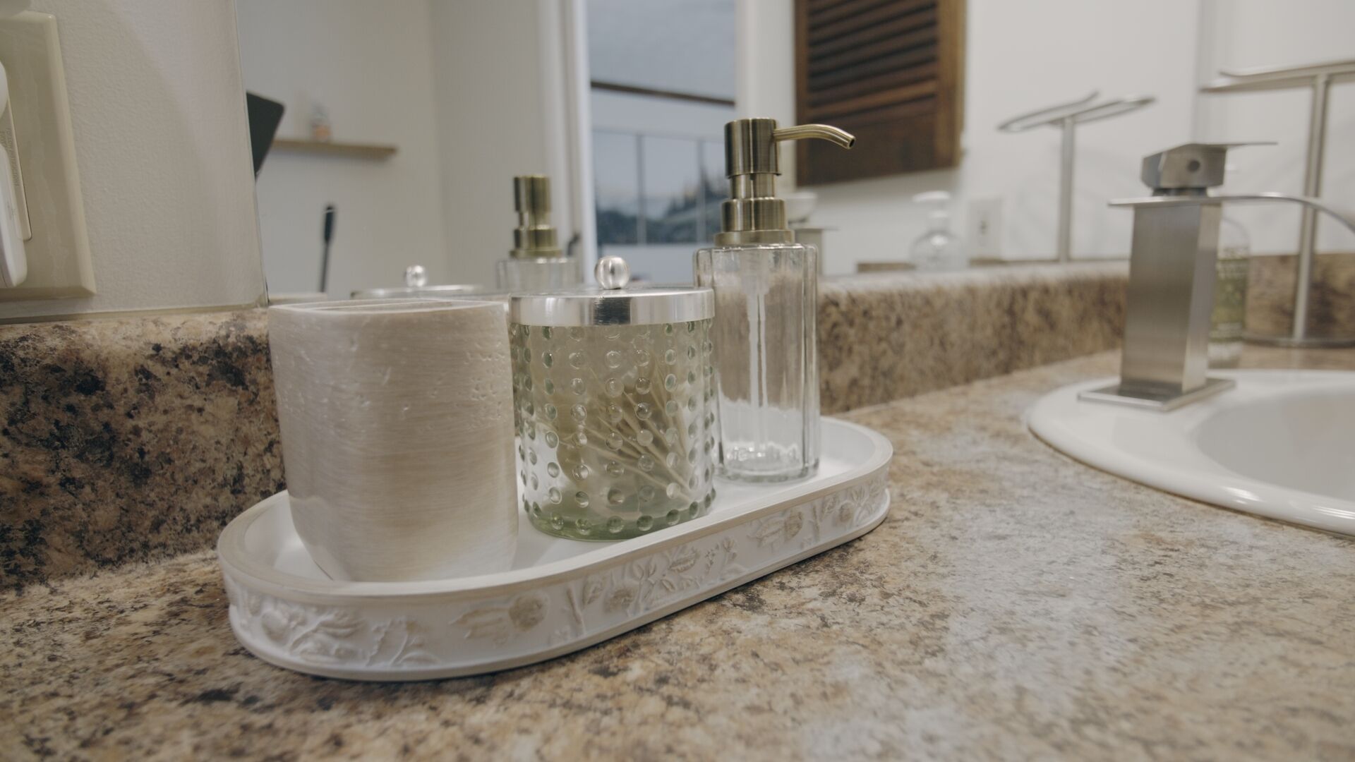 A bathroom vanity with a granite countertop, a white sink, and a mirror.