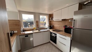Een moderne keuken met witte kastjes, een roestvrijstalen koelkast en een vaatwasser.