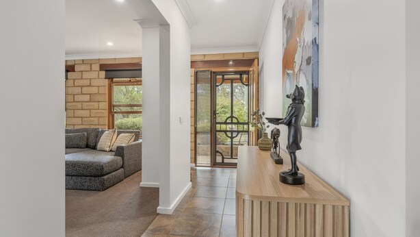 A hallway with a wooden bench, a statue, and a painting on the wall. - Route 86 Bright stunning holiday home with private pool. (Bright)