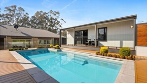 A modern house with a swimming pool, a covered patio, and a view of trees. - Route 86 Bright stunning holiday home with private pool. (Bright)