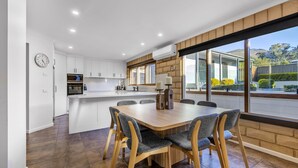 A modern kitchen with white cabinets, a built-in oven, and a large island with seating. - Route 86 Bright stunning holiday home with private pool. (Bright)