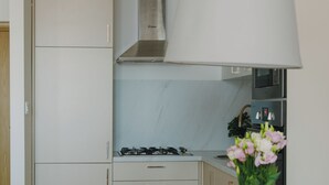 Ett modernt kök med en gasspis, en stor taklampa och en matplats med ett bord och stolar.