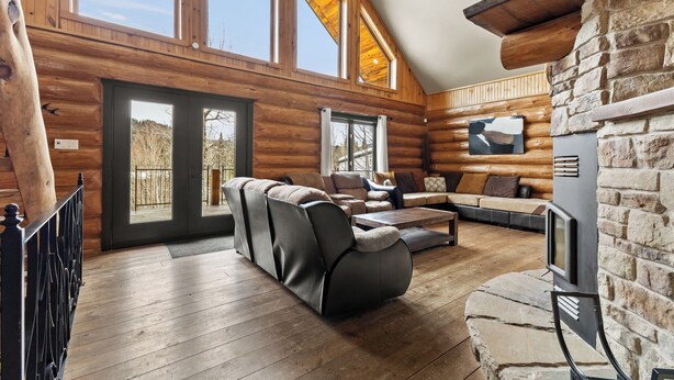 Ein Blockhaus-Interieur mit Kamin, Holzwänden, einer Couch und einem großen Fenster.