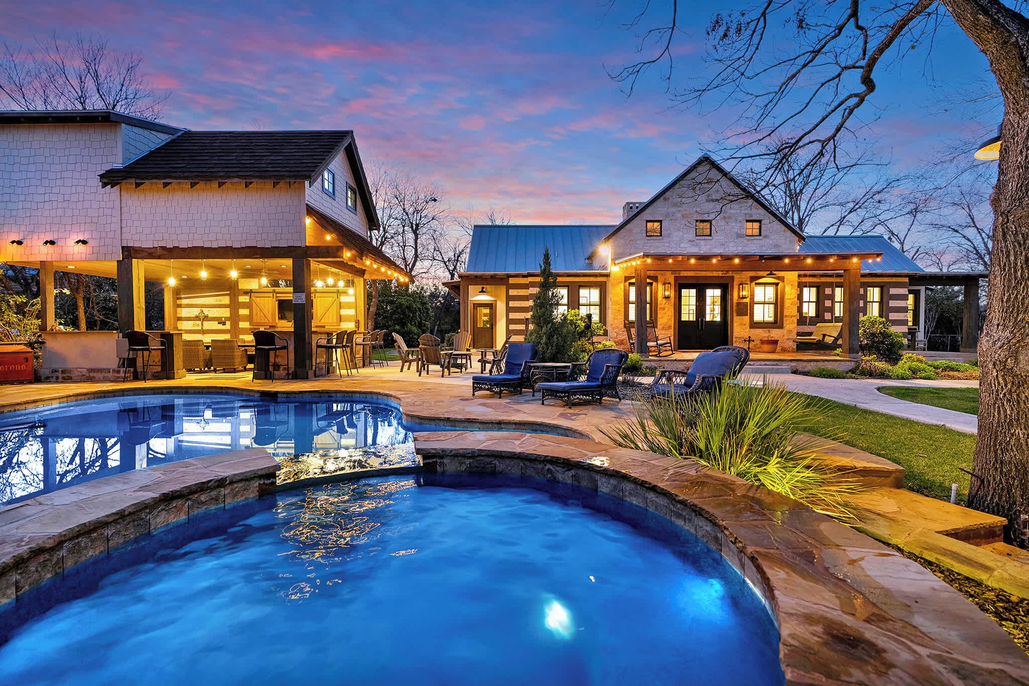 A house with a swimming pool, outdoor seating, and a well-lit patio area.