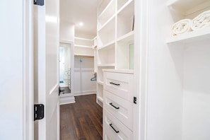 Un couloir étroit avec des meubles de rangement blancs et un plancher en bois.