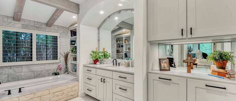 Un baño moderno con una bañera grande, baldosas de mármol y muebles empotrados.