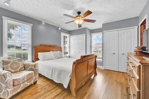 Ein Schlafzimmer mit einem hölzernen Bett, einem Deckenventilator und einer Kommode.