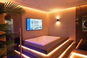 Un baño moderno con una bañera grande, una pantalla digital que muestra información de la habitación e iluminación ambiental.