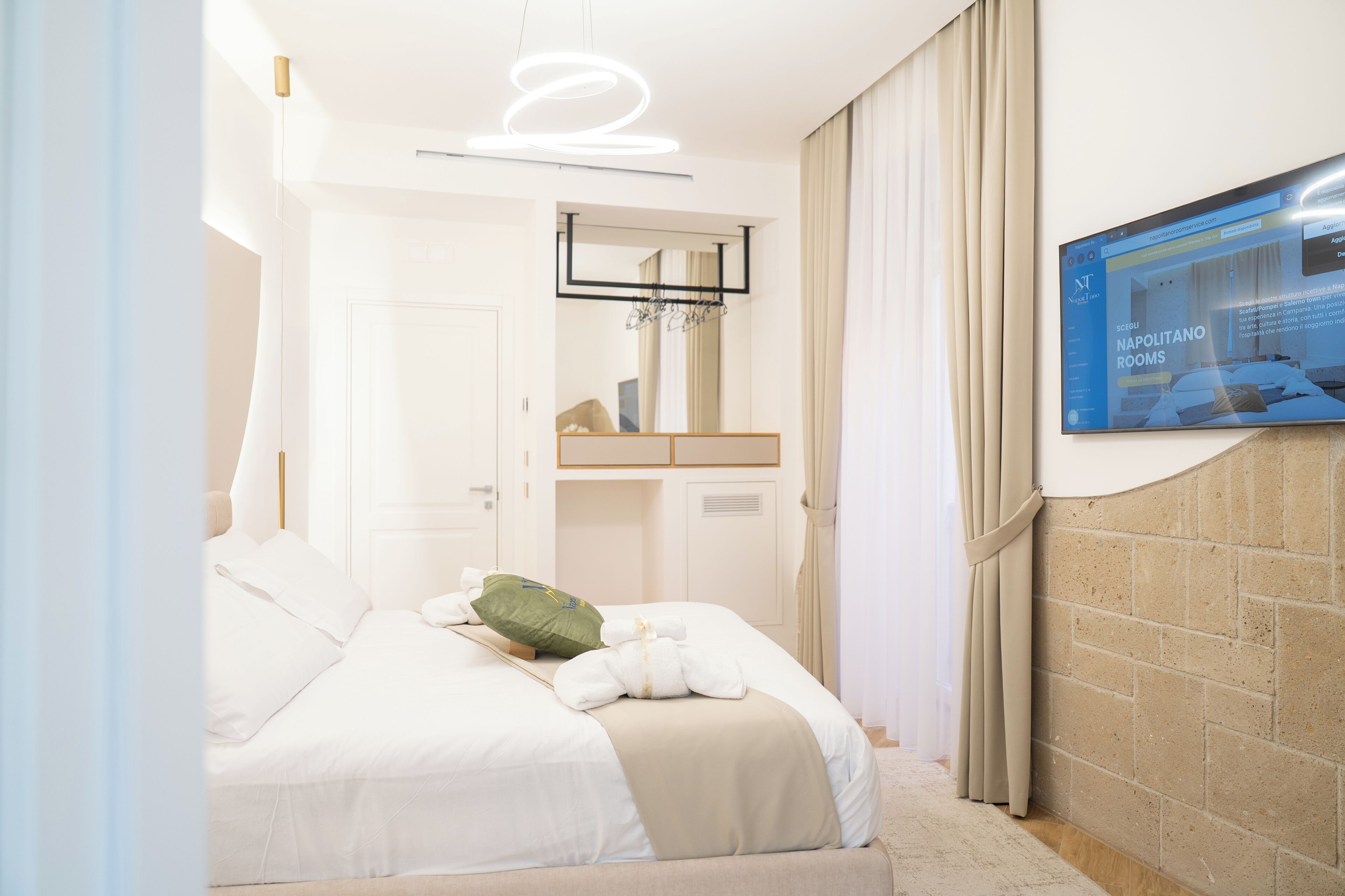 A hotel room with a bed, a television mounted on the wall, a mirror, and a door.