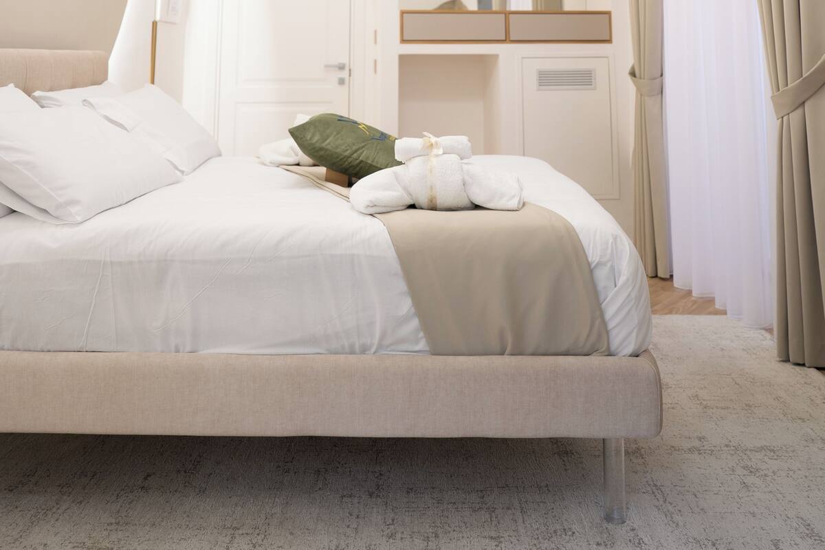 Quarto com cama, luminária pendente, espelho e porta.