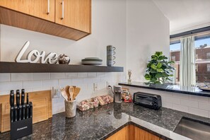 Eine moderne Küche mit Holzschränken, einer Marmorarbeitsplatte, einem Toaster und einem Blumentopf.